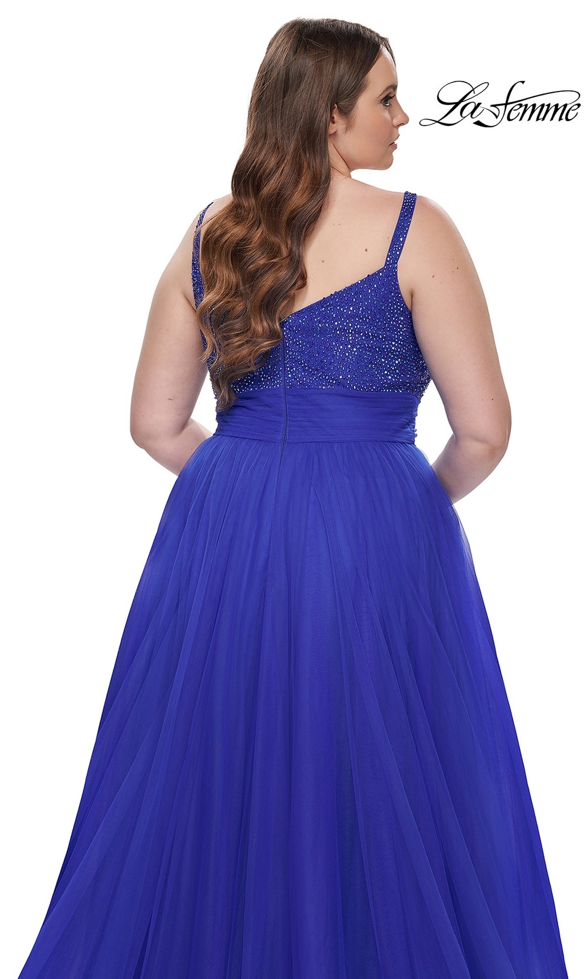 A woman is shown from the back wearing La Femme Long Prom Dress 31251, a plus-size royal blue gown with a sleeveless beaded bodice and a flowing tulle skirt, set against a white background.